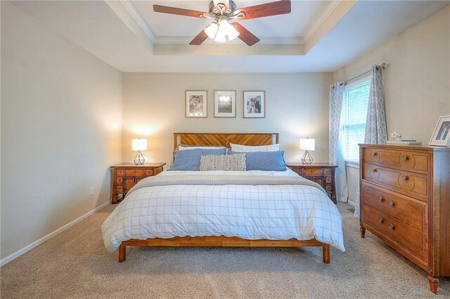 bedroom featuring a tray ceiling, light carpet, ornamental molding, baseboards, and ceiling fan