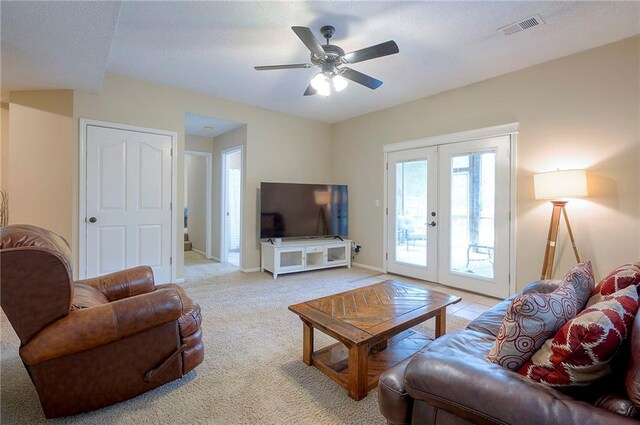 living area with french doors, light colored carpet, a ceiling fan, and baseboards