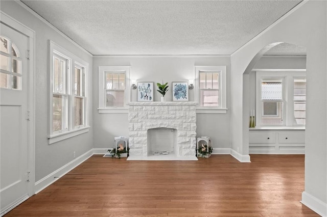 unfurnished living room with crown molding, a textured ceiling, and wood finished floors