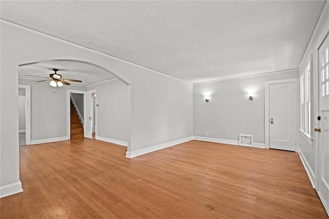 unfurnished living room featuring a ceiling fan, a textured ceiling, visible vents, arched walkways, and light wood-style floors