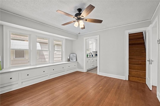 spare room with a ceiling fan, a textured ceiling, a sink, and light wood finished floors
