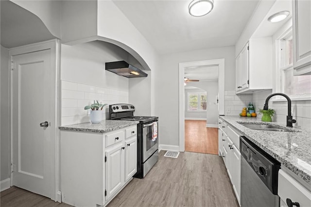 kitchen featuring exhaust hood, ceiling fan, appliances with stainless steel finishes, a sink, and decorative backsplash