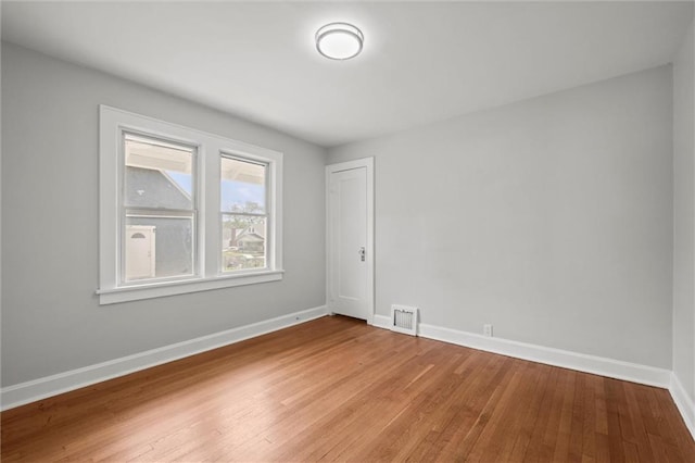empty room with baseboards, visible vents, and light wood-type flooring