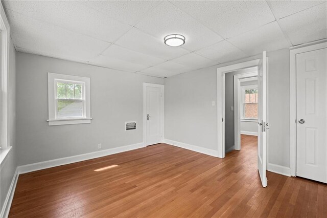 interior space with multiple windows, light wood finished floors, and a paneled ceiling