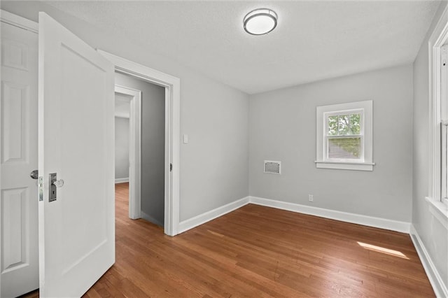 unfurnished bedroom with baseboards, wood finished floors, and visible vents