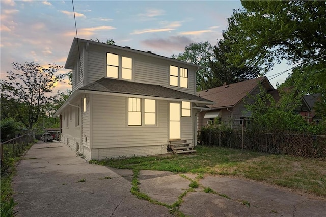 rear view of property with concrete driveway, fence, and entry steps