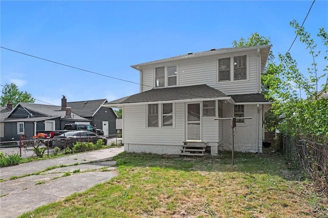 view of front of home with entry steps, a fenced backyard, and a front lawn