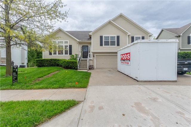 tri-level home with a garage, a front lawn, and concrete driveway
