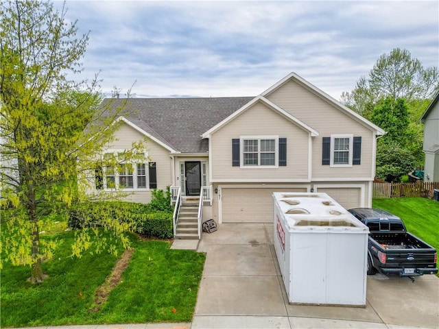 split level home with a garage, fence, a front yard, and concrete driveway