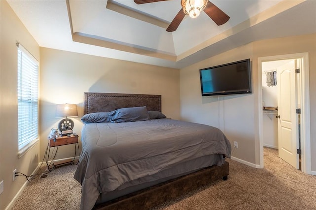 carpeted bedroom featuring baseboards, a raised ceiling, and ceiling fan