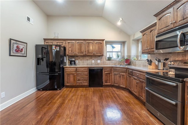 kitchen featuring decorative backsplash, visible vents, a sink, black appliances, and dark wood-type flooring