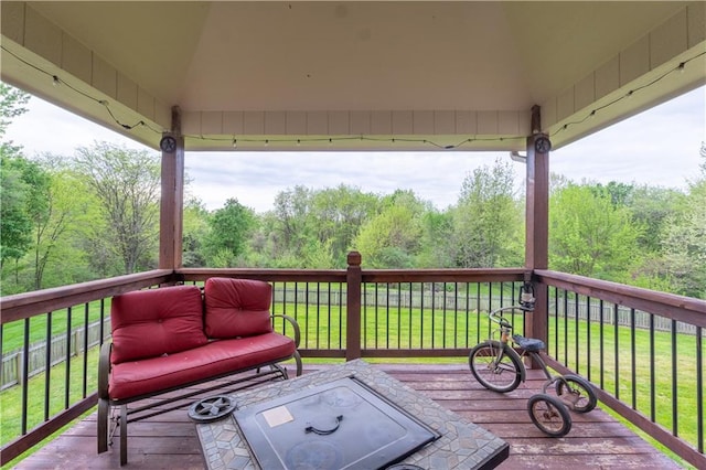 wooden deck with a lawn and a forest view