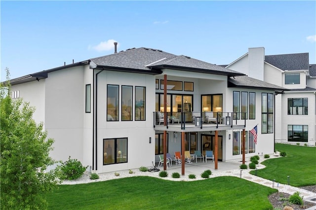rear view of property with stucco siding, a patio, a balcony, and a yard