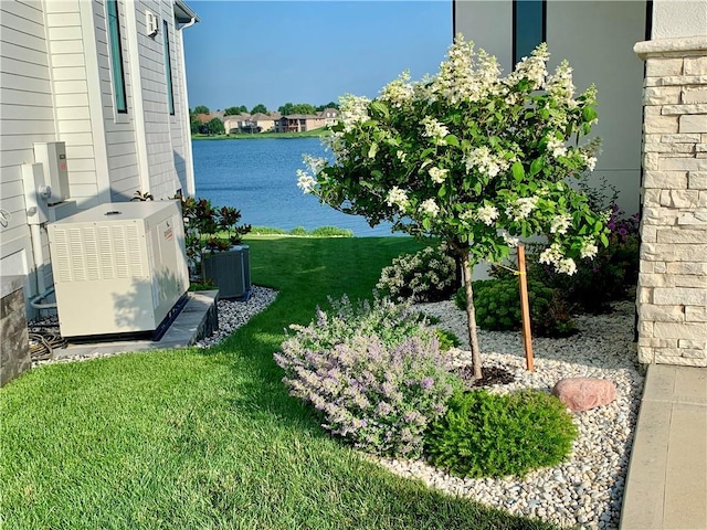 view of grassy yard featuring a water view and central air condition unit