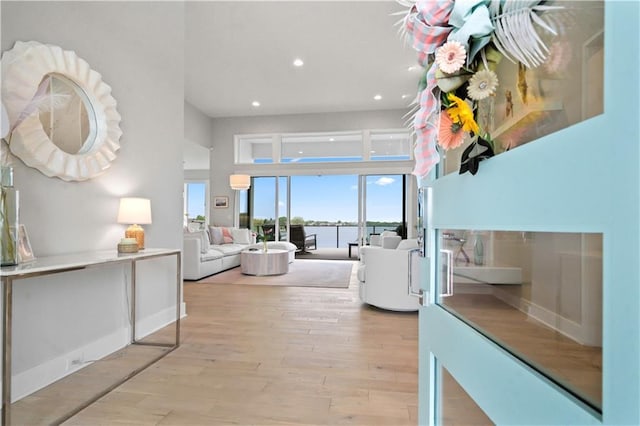 hall featuring light wood-type flooring, recessed lighting, and a water view
