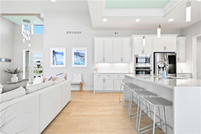 kitchen with appliances with stainless steel finishes, a breakfast bar area, light wood-style flooring, recessed lighting, and white cabinets