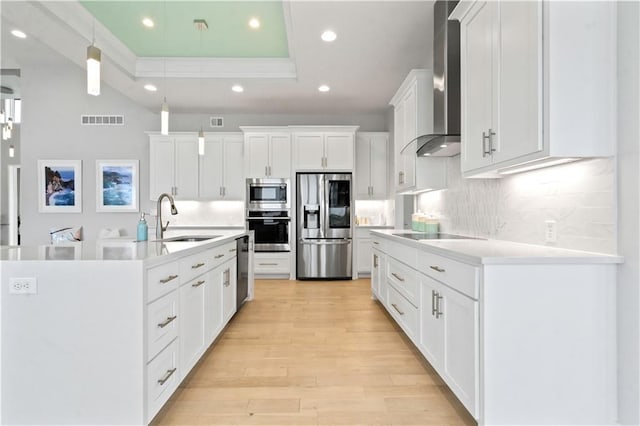 kitchen with appliances with stainless steel finishes, a sink, wall chimney exhaust hood, recessed lighting, and decorative backsplash