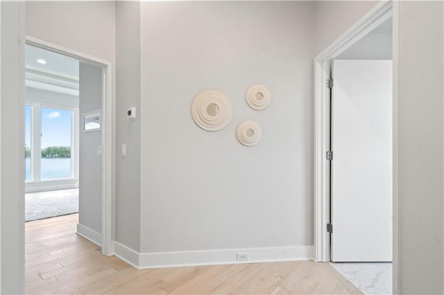 hall with baseboards, light wood-style flooring, and a water view