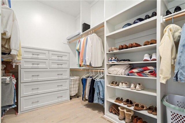 walk in closet with light wood-style flooring