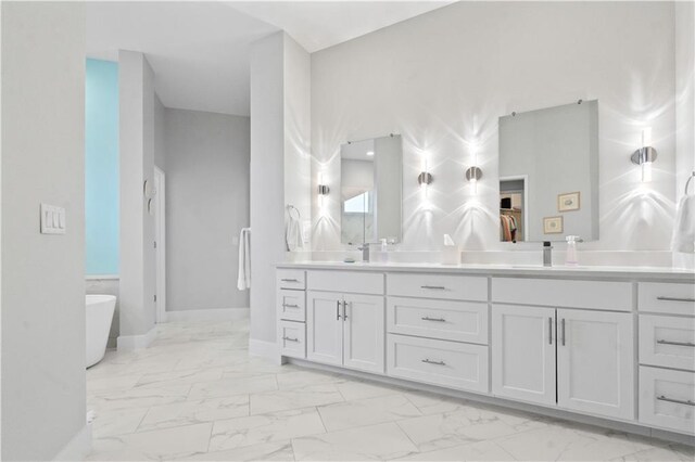 bathroom featuring marble finish flooring, double vanity, a freestanding bath, and baseboards