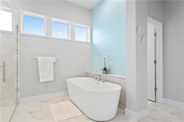 full bathroom featuring marble finish flooring, a marble finish shower, a freestanding tub, and baseboards