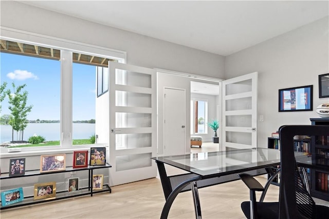 office area with healthy amount of natural light, a water view, and wood finished floors