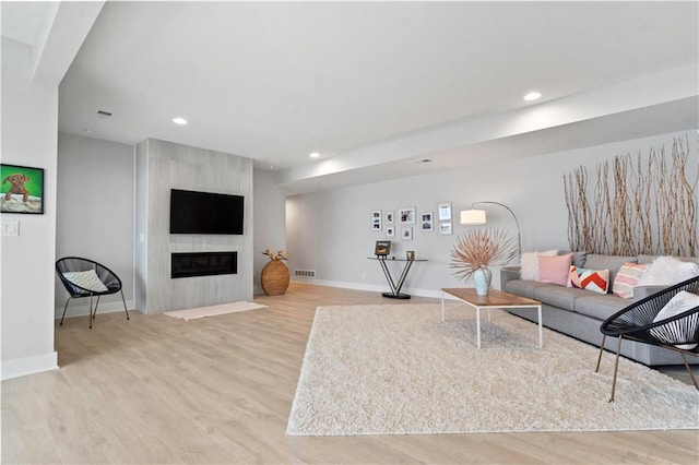 living room featuring wood finished floors, baseboards, recessed lighting, and a fireplace