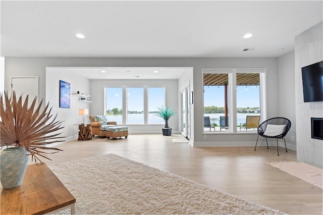 living room with wood finished floors, a large fireplace, recessed lighting, and baseboards