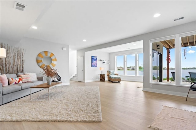 living room with stairway, wood finished floors, recessed lighting, baseboards, and a water view