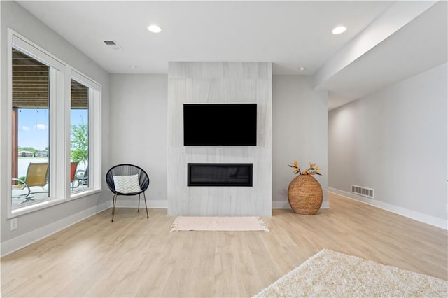 living area with a fireplace, wood finished floors, baseboards, and recessed lighting