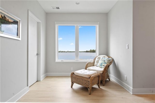 living area with light wood-style flooring, baseboards, and a water view