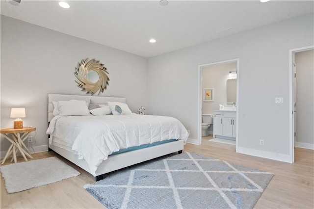 bedroom featuring light wood-type flooring, baseboards, recessed lighting, and ensuite bath