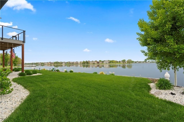 view of grassy yard featuring a deck with water view