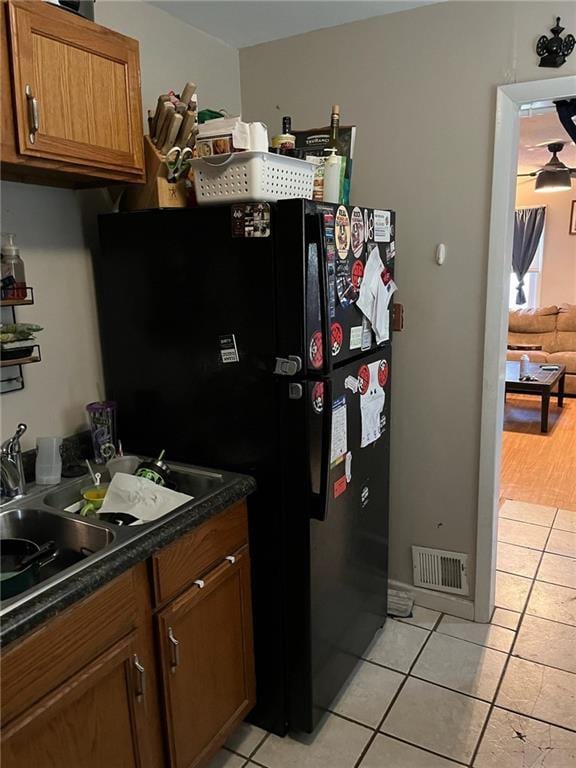 1114 Dakota St, Leavenworth, KS 66048 - kitchen featuring brown cabinets, freestanding refrigerator, light tile patterned flooring, visible vents, and dark countertops