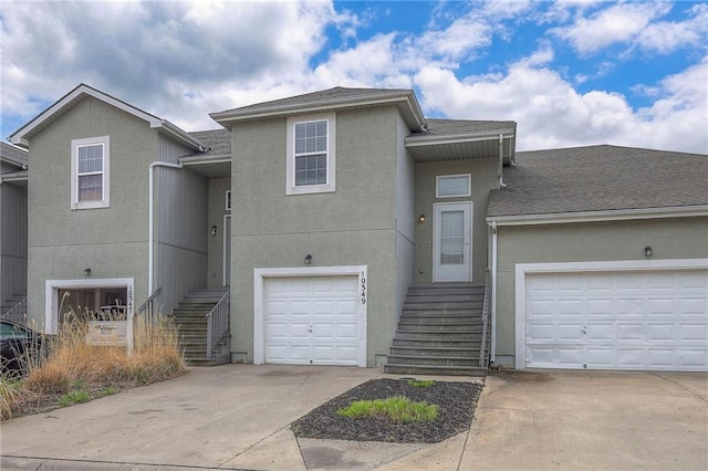 view of front facade with concrete driveway, stairs, and stucco siding