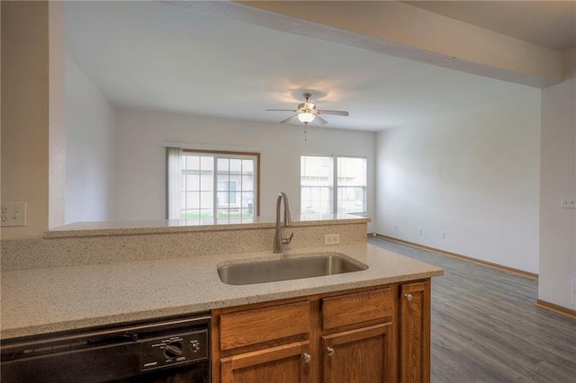kitchen with a ceiling fan, light stone countertops, brown cabinets, a sink, and black dishwasher