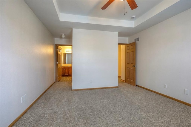 unfurnished bedroom featuring carpet flooring, baseboards, visible vents, and a raised ceiling