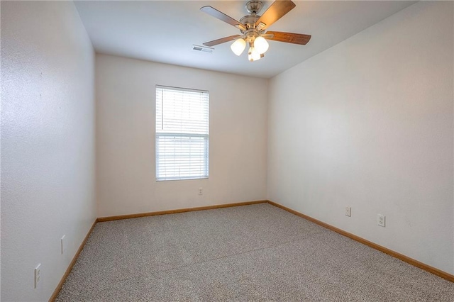 carpeted empty room with baseboards, a ceiling fan, and visible vents
