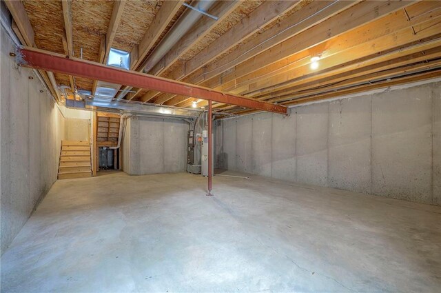 unfinished basement featuring stairs and water heater