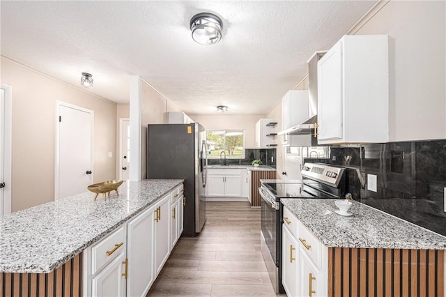 9505 E 79th St, Raytown, MO 64138 - kitchen featuring a textured ceiling, white cabinets, appliances with stainless steel finishes, light wood finished floors, and backsplash