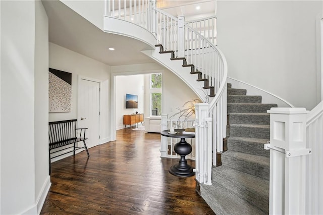 interior space with stairway, wood finished floors, and a towering ceiling