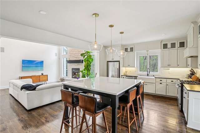 kitchen with a sink, a fireplace, tasteful backsplash, appliances with stainless steel finishes, and open floor plan