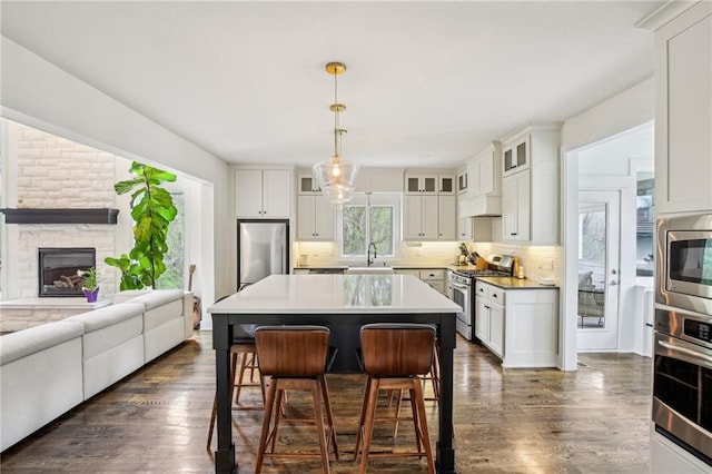 kitchen with a sink, tasteful backsplash, a breakfast bar, appliances with stainless steel finishes, and open floor plan