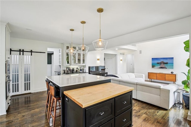 kitchen with butcher block countertops, a barn door, dark cabinetry, white cabinetry, and stainless steel oven