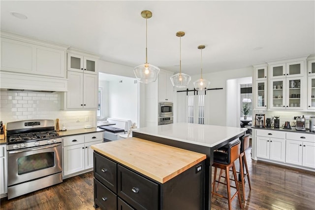 kitchen featuring white cabinets, appliances with stainless steel finishes, a center island, butcher block counters, and custom exhaust hood