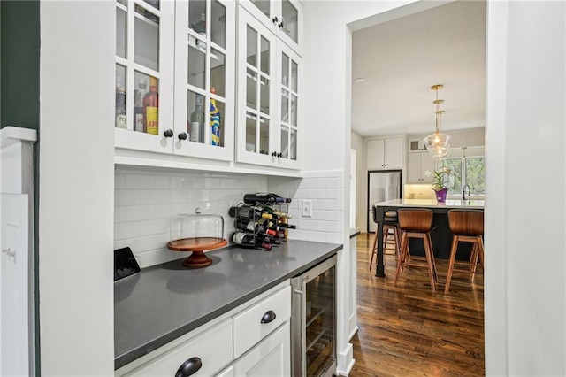 bar featuring tasteful backsplash, beverage cooler, freestanding refrigerator, dark wood-type flooring, and a dry bar