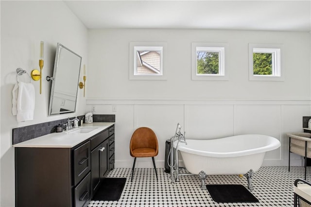 bathroom featuring a freestanding bath, a wainscoted wall, vanity, and a decorative wall