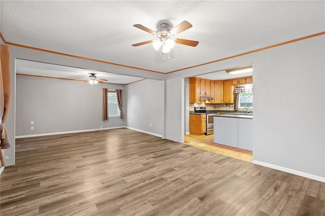 unfurnished living room with light wood-style flooring, ceiling fan, ornamental molding, and a textured ceiling