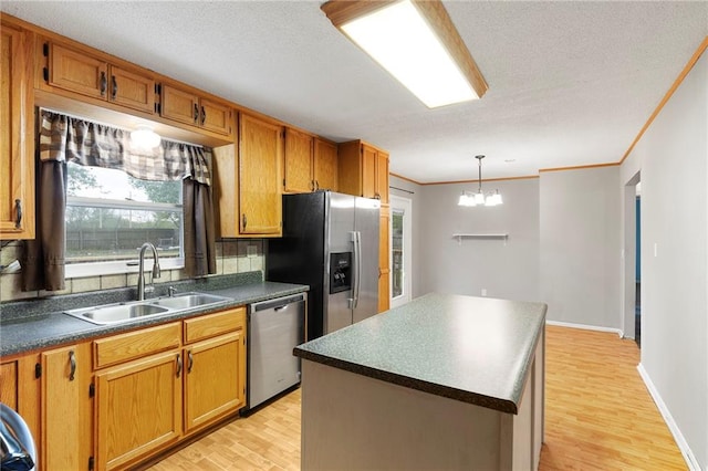 kitchen featuring appliances with stainless steel finishes, brown cabinets, dark countertops, a sink, and light wood-type flooring