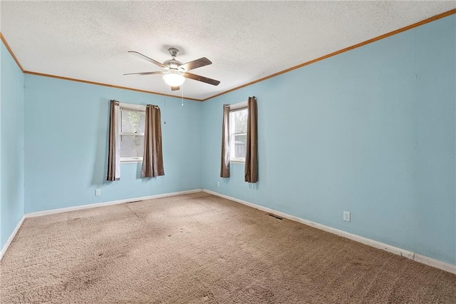empty room featuring a ceiling fan, carpet, baseboards, ornamental molding, and a textured ceiling